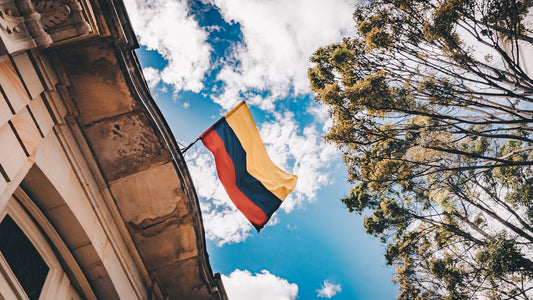 colombian flag flying on the wall of a building looking up to the blue sky 